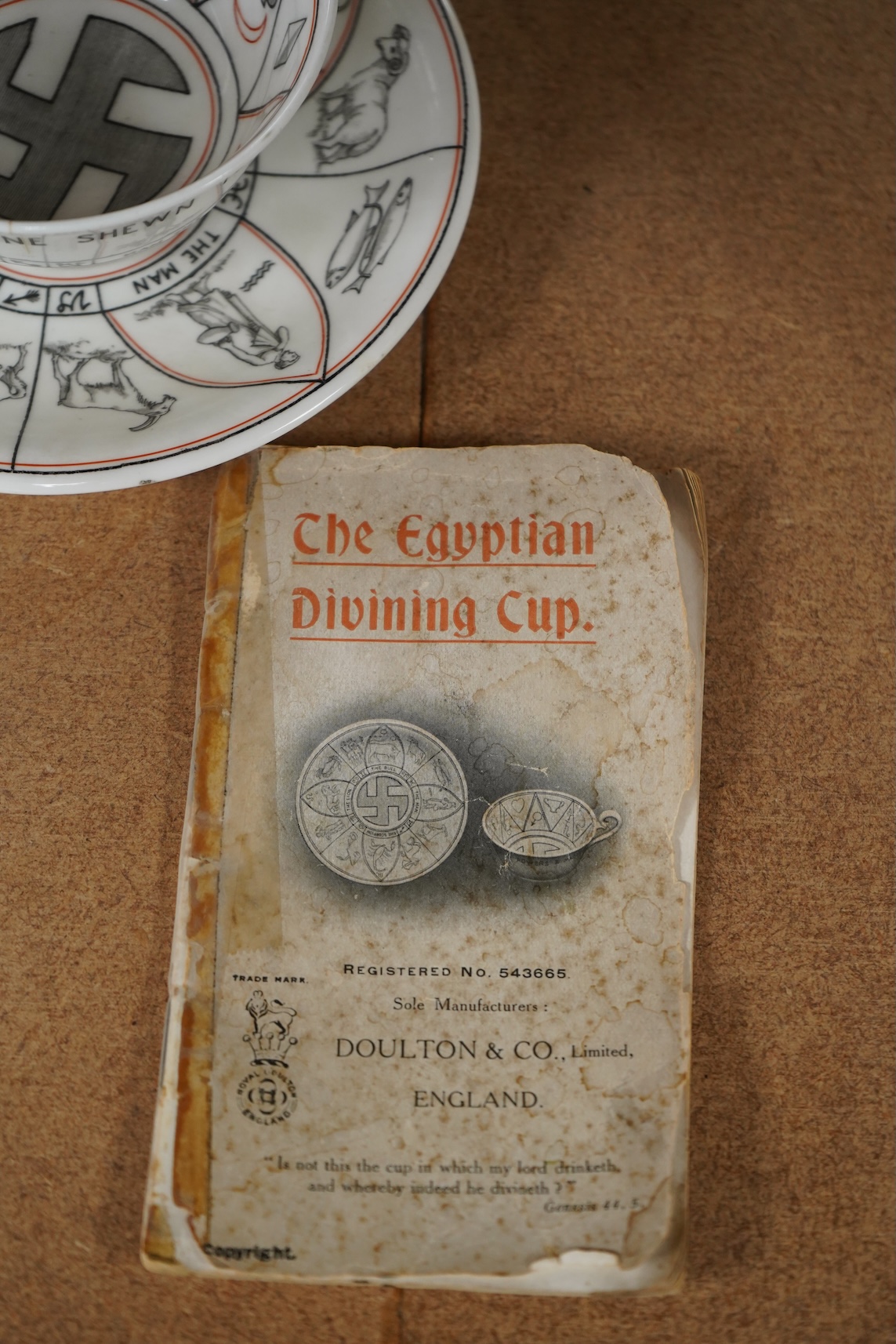 A Royal Doulton 'The Egyptian Divining cup and saucer', with booklet, numbered RN543665